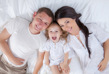 Fototapeta na wymiar Happy family lying on a bed together in the bedroom