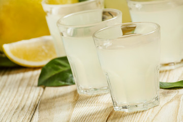 Home lemon liqueur and fresh lemons and limes on a wooden backgr