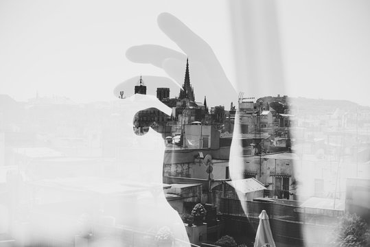 Double exposure with Barcelona and hand near the window