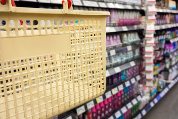 Shopping with cream plastic basket. Browsing the available goods in supermarket.