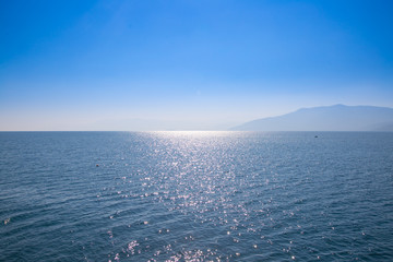 Paysage marin avec ciel bleu et eaux, avec des terres lointaines cachées dans la brume.