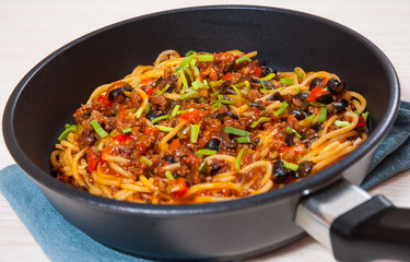 spaghetti with vegetables and minced meat in a frying pan