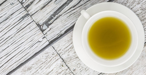 Japanese green tea in white cup over wooden background