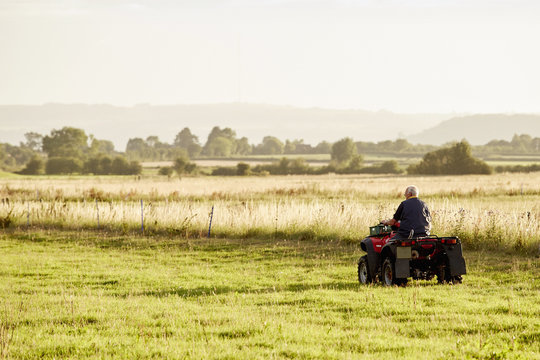 A man on a quadbike driving across a field. 