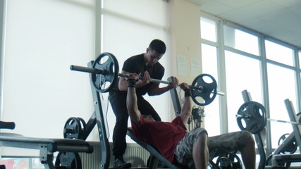 The bodybuilder does exercise with a bar - Powered by Adobe