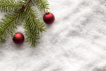 Christmas baubles and branch of spruce tree on snow