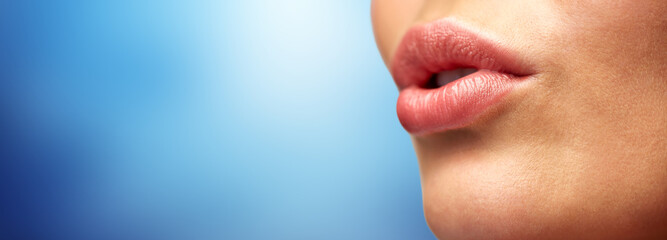close up of young woman lips over blue