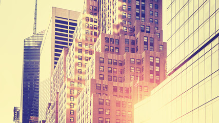 Vintage toned high key picture of skyscrapers against sun, NYC.