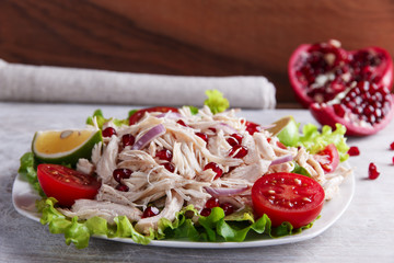 salad of white chicken meat with tomato and pomegranate seeds