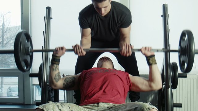 The bodybuilders does exercise with a bar