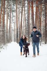 Fototapeta na wymiar Young Couple with a Dog Having Fun in Winter