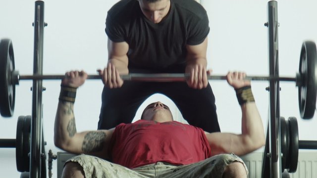 The bodybuilders does exercise with a bar