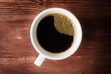 Top view of cup with coffee over wooden background