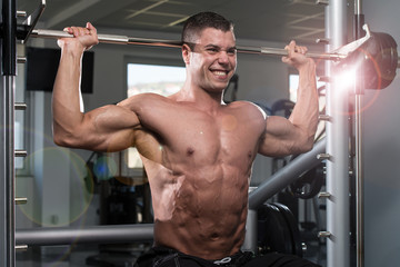 Fototapeta na wymiar Male Bodybuilder Doing Heavy Weight Exercise For Shoulders
