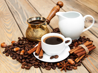 coffee cup with coffee beans,    milk jug and turk on a wooden b