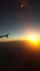 Skrzydło samolotu przy zachodzie słońca w chmurach