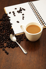 Cup of coffee and beans with white book