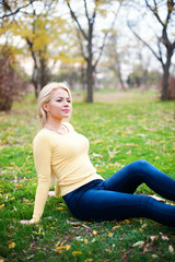 Obraz premium Young beautiful woman sitting on grass looking away