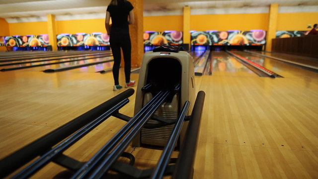 Girl throws a bowling ball at the pins
