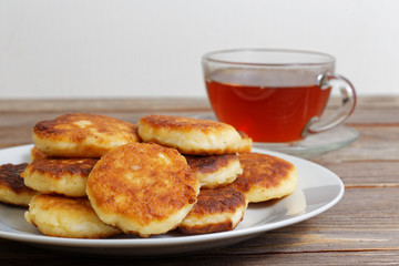 White plate with cottage cheese pancakes and cup of tea