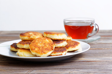 White dish with cottage cheese pancakes and cup of tea