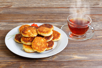 White plate with cottage cheese pancakes and cup of tea