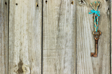Bronze skeleton key hanging from rope on antique rustic wood door