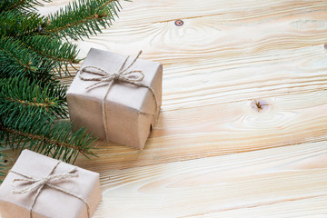 Christmas gifts packaged in kraft paper and  jute rope constricted  on wooden table with Christmas tree . top view, free space for text
