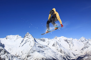Flying snowboarder on mountains. Extreme sport.