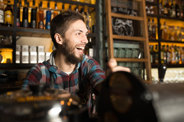 Man barista preparing coffee for his customers while laughing