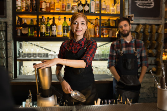 Portrait of a female and male barista standing inside their coffee house