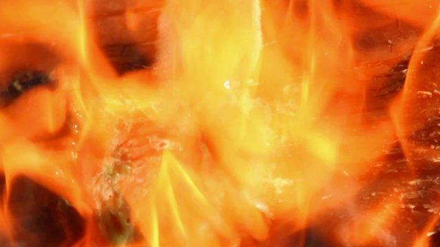 Piece of green colored plastic material burning, melting and dissolving in flames; close up; no people