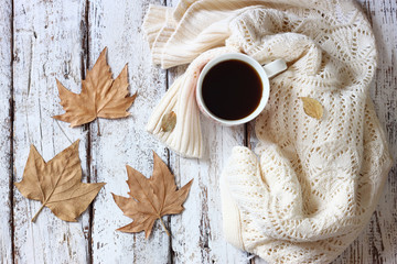 Fototapeta na wymiar top view image of white cozy knitted sweater with to cup of coffee and autumn leaves on a wooden table