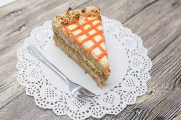 Fresh tasty sweet piece of  carrot cake on a white napkin and a dessert fork on a wooden background