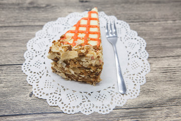 Fresh tasty sweet piece of  carrot cake on a white napkin and a dessert fork on a wooden background