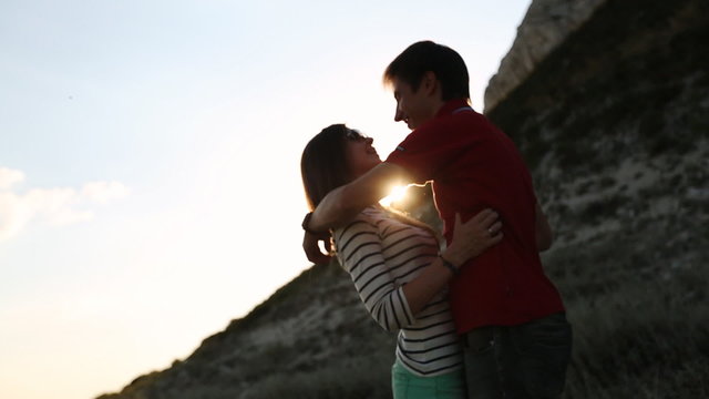 a loving couple kissing in the sunset near the mountain