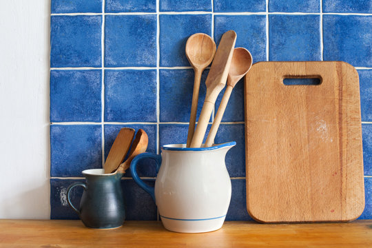 Kitchen Still Life. Interior With Vintage Accessories. Blue Tiles Ceramic Wall Background, Retro Pitchers, Cutting Desk, Wooden Spoons