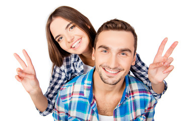 Pretty young woman embracing her boyfriend showing two fingers