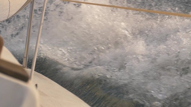 Closeup of white sail boat sailing through the waves. Beautifully shot in slow motion