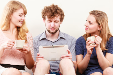 Friends relaxing browsing internet on tablet.