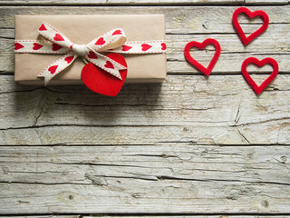 valentine gift box and red heart shapes, on wooden board