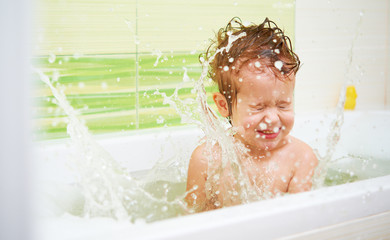 happy baby child bathes in a bath sprinkles and plays with the f