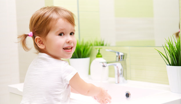 child little girl washes her hands in bathroom