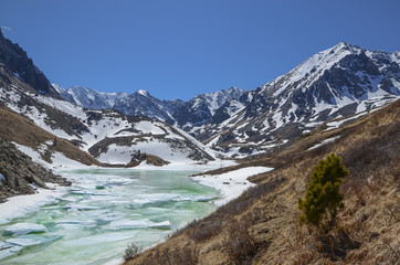 Fototapeta na wymiar Lake in the mountains. Lake under the ice in the snowy mountains of Altai.