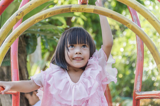 Asian girl dressed in Thailand playing in playground.