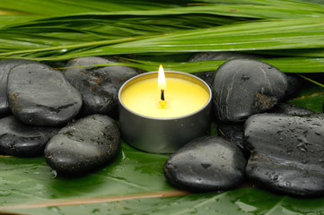  candle and stones on wet banana leaf