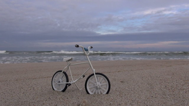 Little toy bicycle on the beach by the sea 