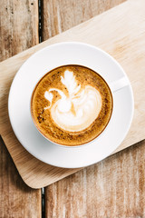 Selective focus cup of hot latte art coffee on wooden table,focus at white foam