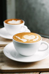 Selective focus cup of hot latte art coffee on wooden table,focus at white foam