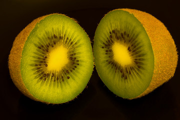 Kiwi fruit cut into halves shot against a black background.